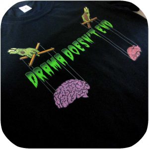camiseta negra con texto en letras verdes que recuerdan a series de terror de los 90. En el dibujo dos manos también verdes sostienen como marionetas a un corazón y un cerebro.